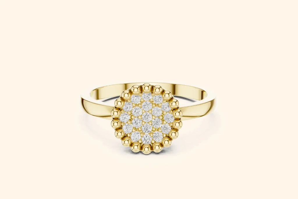 A front view of a stylish ring in bright gold or yellow gold. It showcases a round setting fully paved with diamonds, bordered by a pronounced beaded edge for texture and detail.