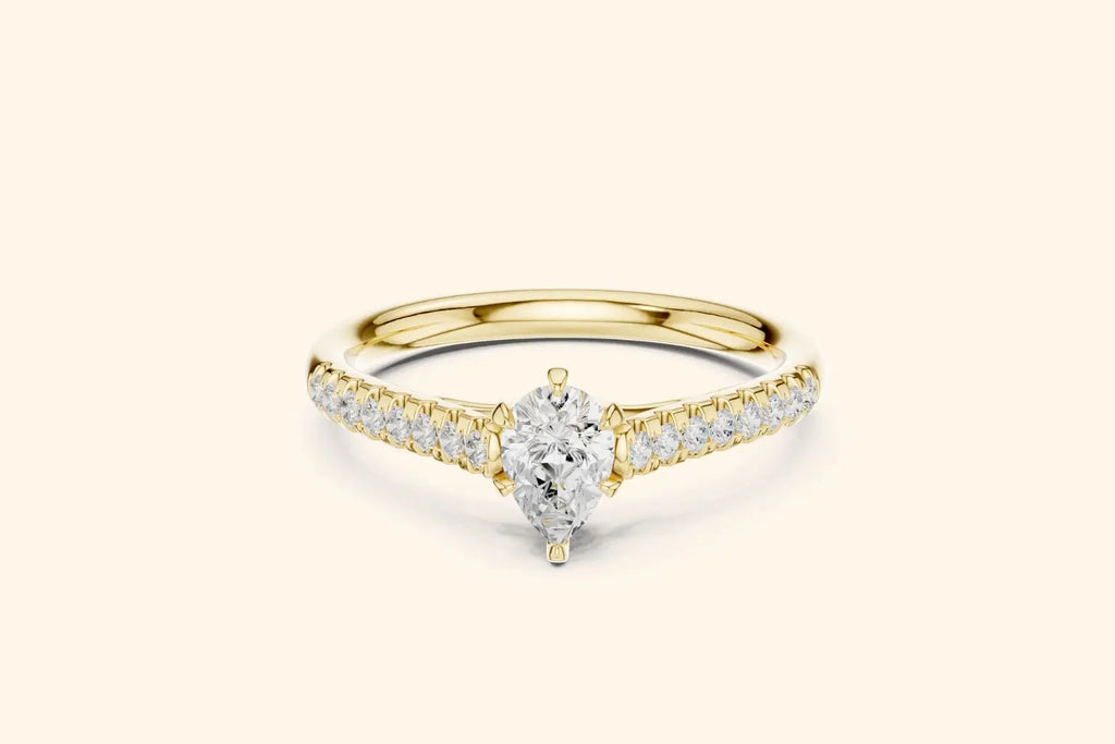 Elegant pure gold engagement ring featuring a sparkling pear-cut center diamond and smaller diamonds set along the band.