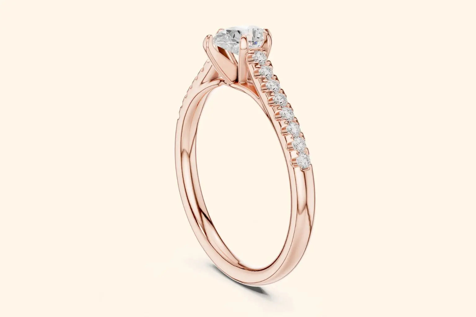 Close-up side view of a rose gold solitaire-style engagement ring with a round center diamond and channel-set diamonds on the shoulder.