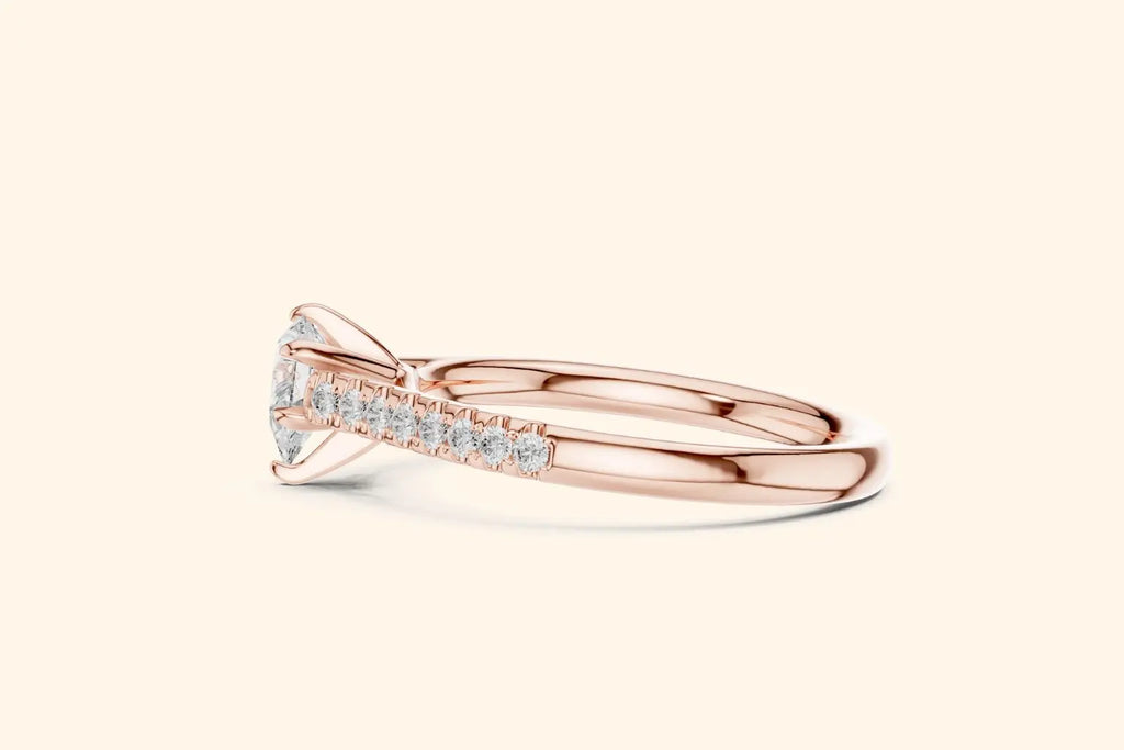 Side view of a rose gold ring band with pave-set diamonds, highlighting the profile of the center stone mounting.