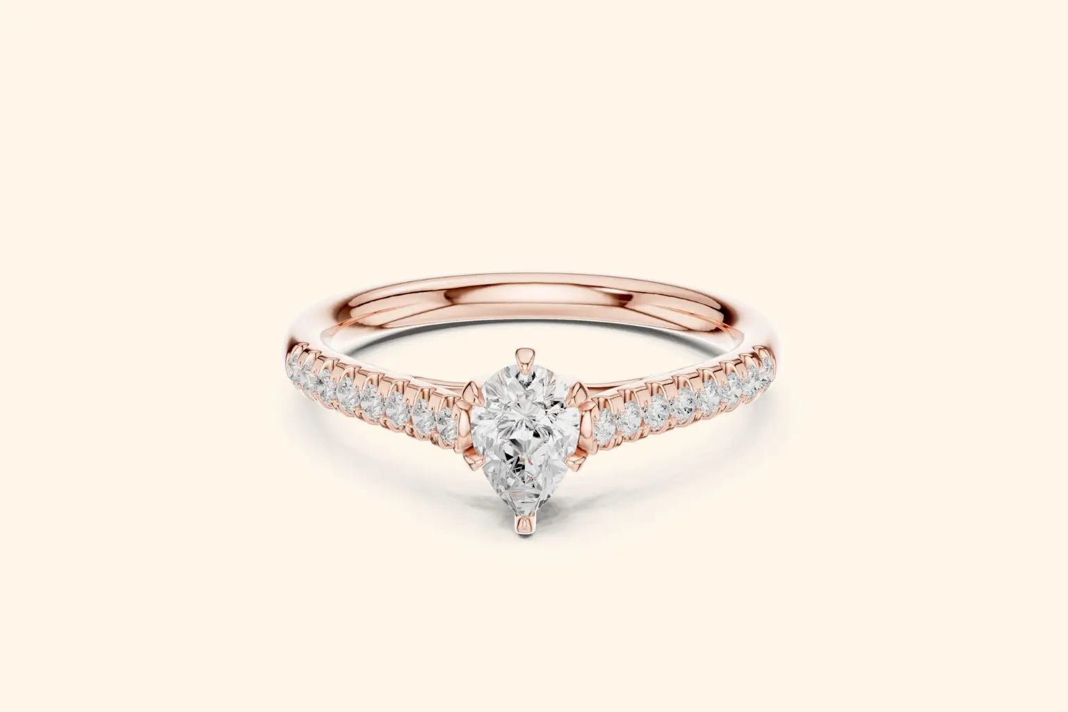 A delicate rose gold engagement ring with a brilliant pear-cut diamond in the center and pave diamonds running down the shank.