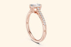 Rose gold engagement ring with a radiant-cut center diamond and a pavé band of small diamonds on each side.