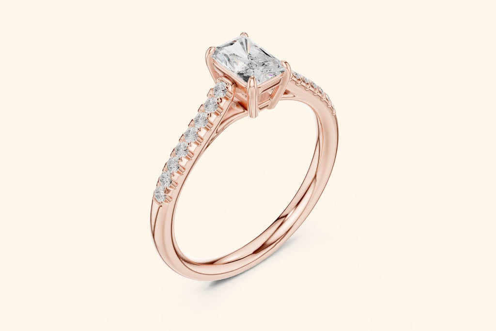 Side view of a rose gold solitaire ring, showing the elevated setting of the radiant-cut diamond and the row of accent diamonds on the band.