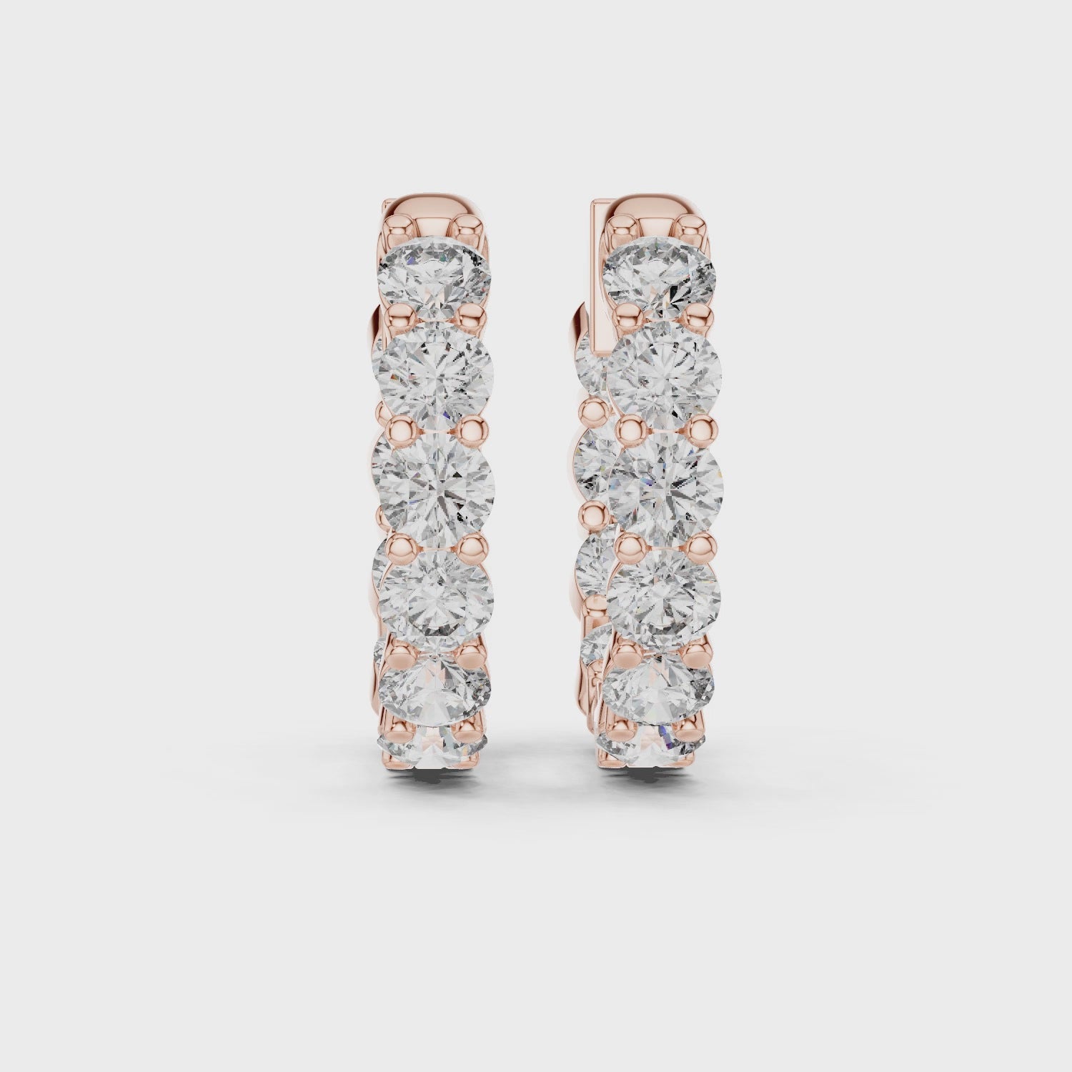Pair of rose gold inside-out eternity diamond hoop earrings on a white background