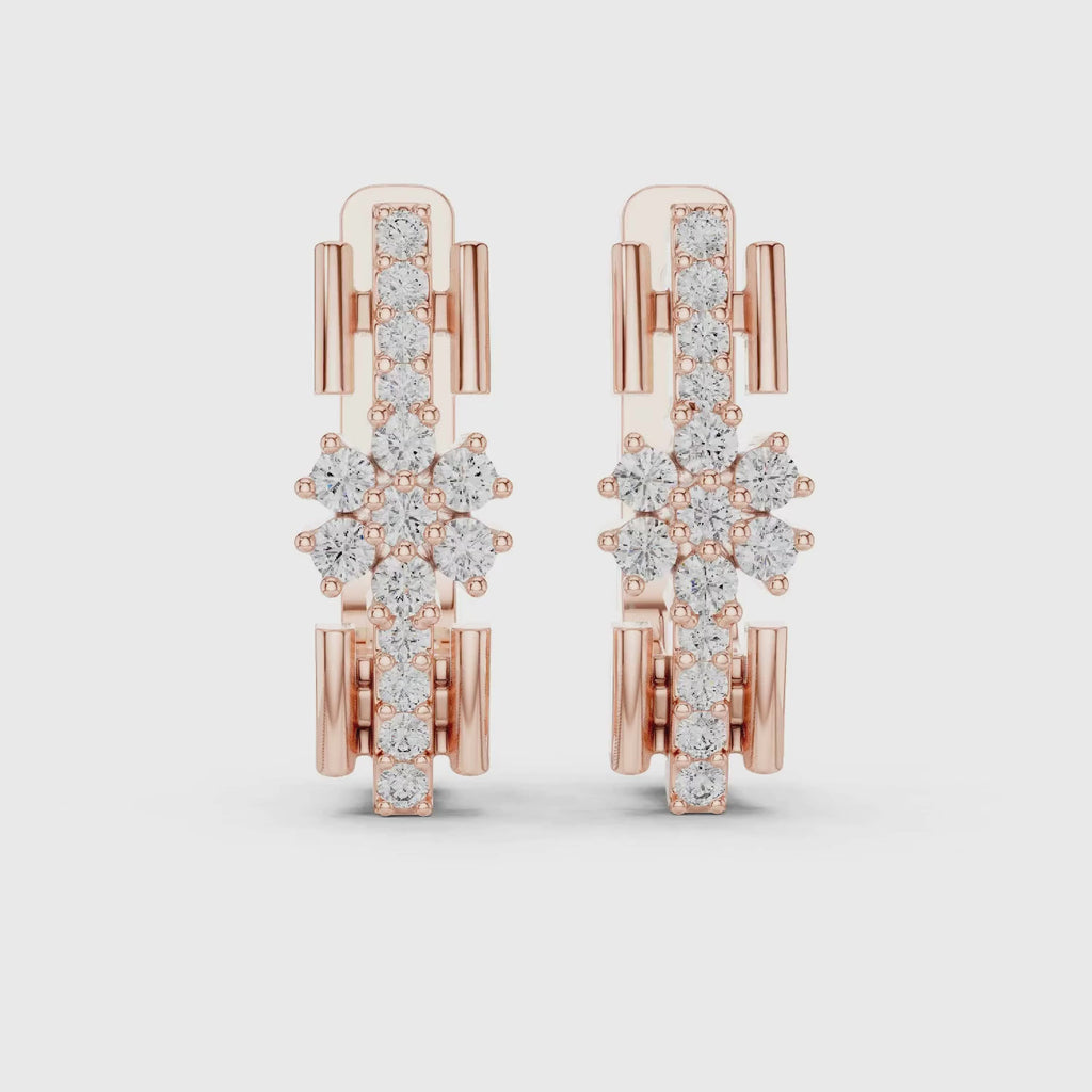 A pair of rose gold huggie earrings featuring a complex, openwork snowflake