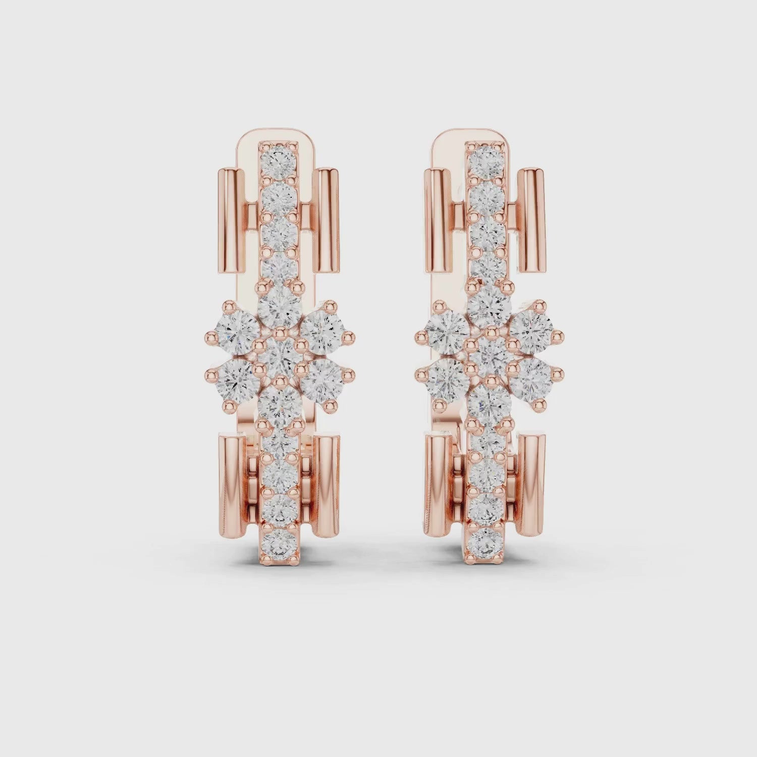 A pair of rose gold huggie earrings featuring a complex, openwork snowflake