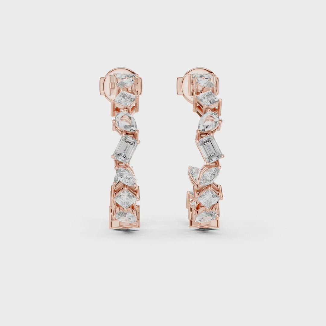 Pair of luxury yellow gold hoop earrings set with mixed-cut diamonds, including baguette and pear-shaped stones, displayed on a black background with a soft textured highlight.