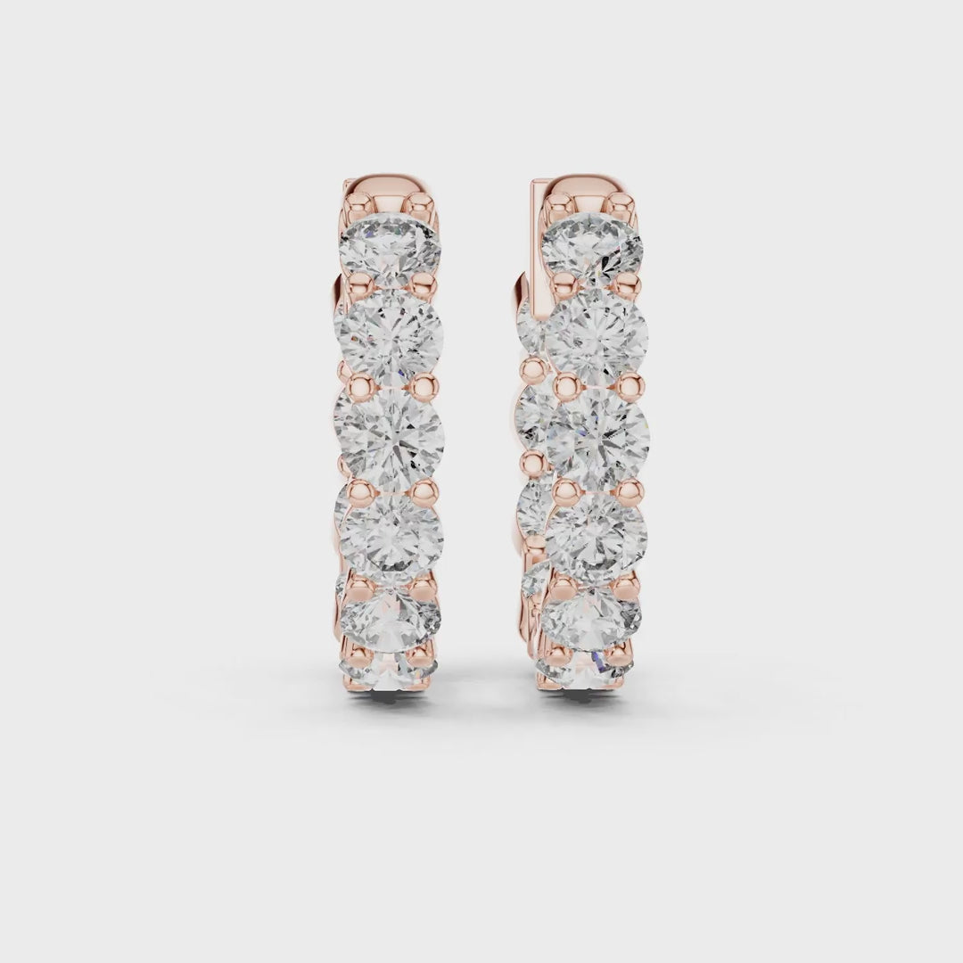 Pair of rose gold inside-out eternity diamond hoop earrings on a white background