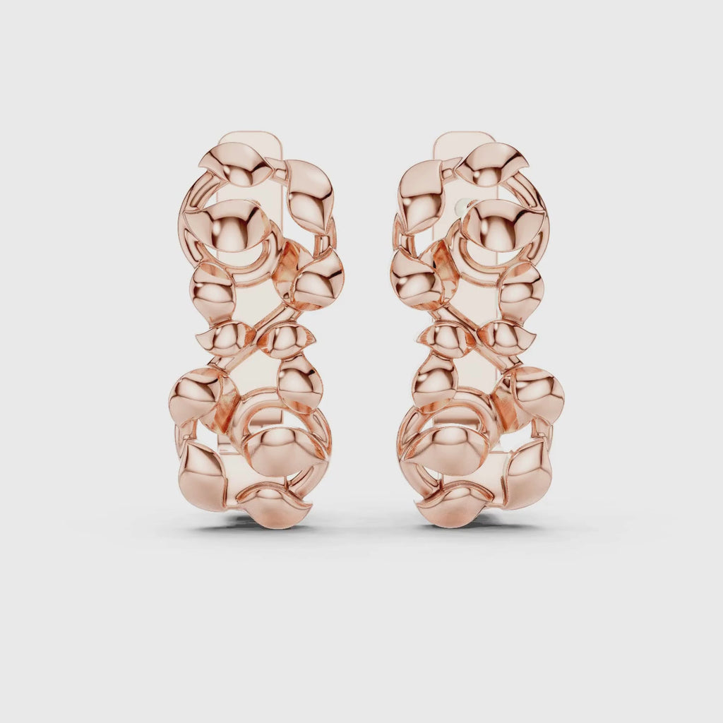 A pair of huggie earrings featuring a detailed