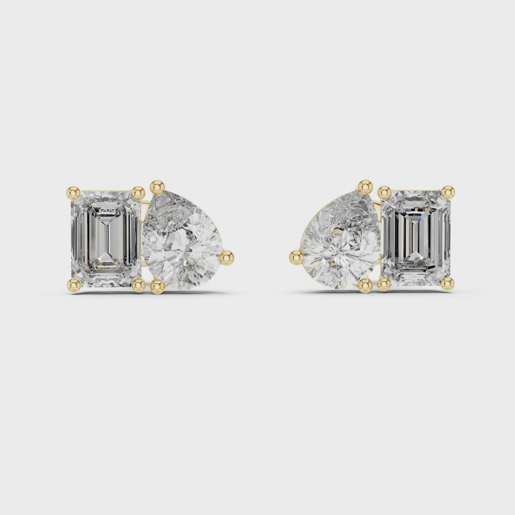 Pair of yellow gold stud earrings featuring a cluster of one pear-cut and one emerald-cut diamond
