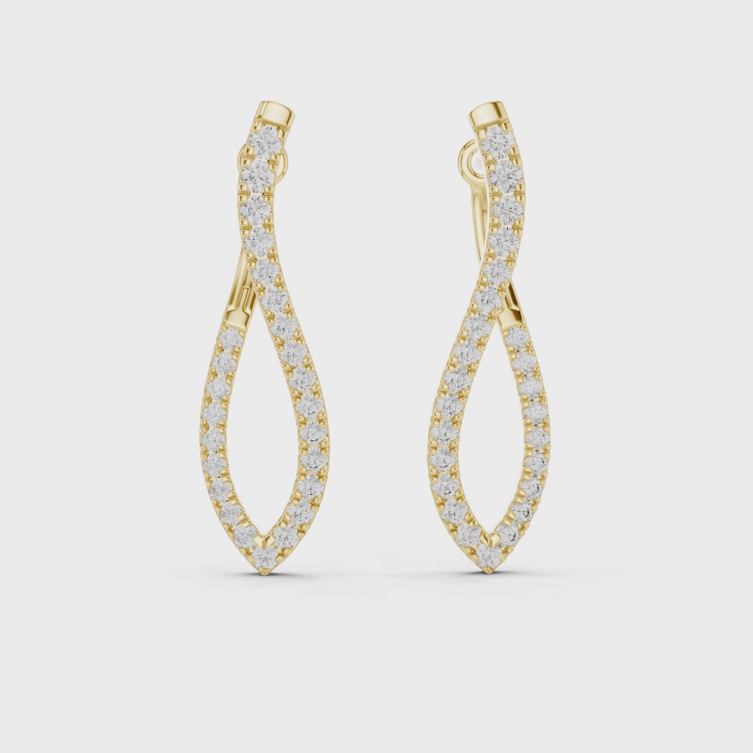 Pair of yellow gold twisted infinity hoop earrings with pave-set diamonds on a white background